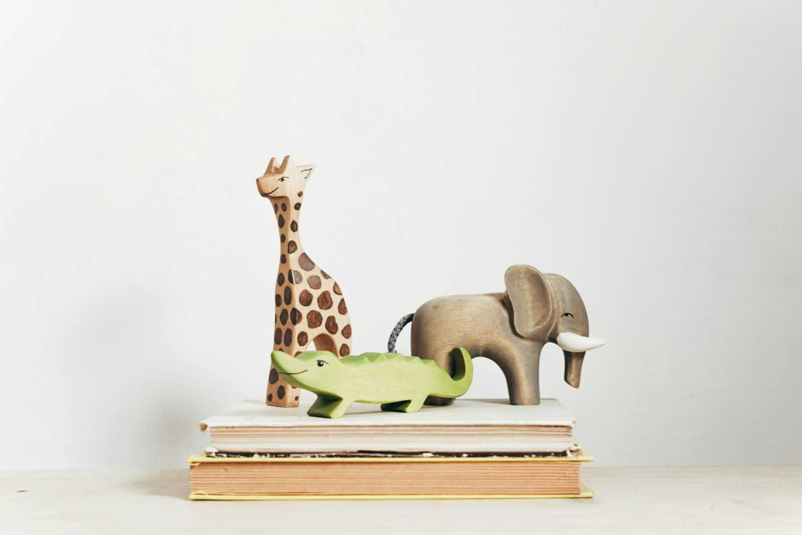 Charming display of wooden animal toys on stacked books, perfect for children's decor.